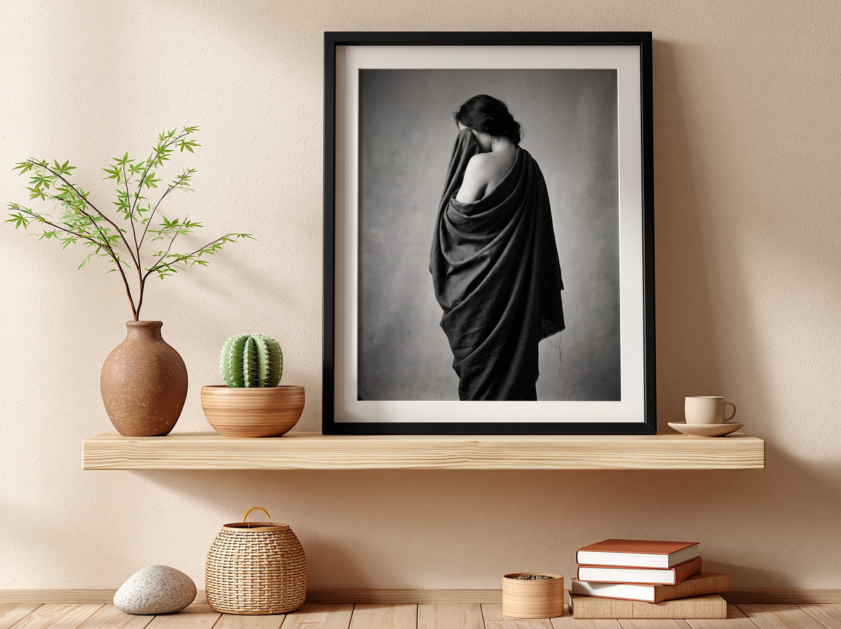 Black and white wall decor of a model draped in flowing dark fabric with soft shadows