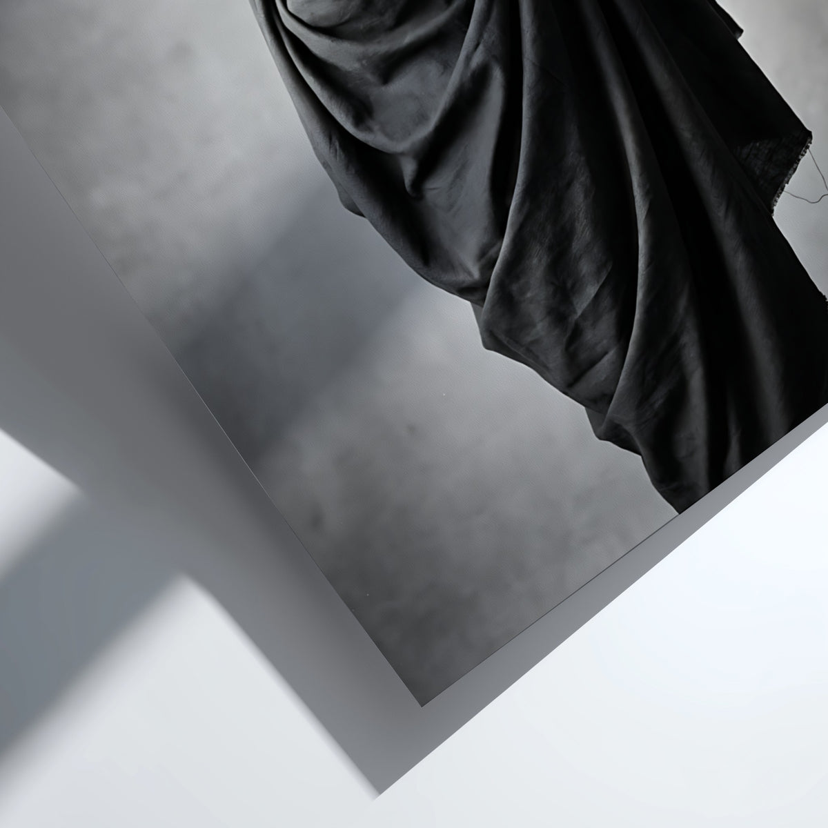 Black and white wall decor of a model draped in flowing dark fabric with soft shadows
