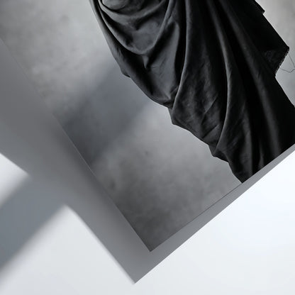 Black and white wall decor of a model draped in flowing dark fabric with soft shadows