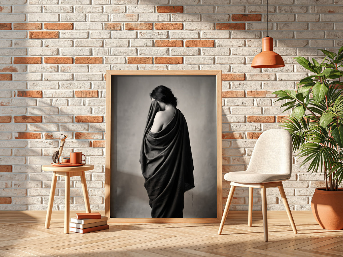 Black and white wall decor of a model draped in flowing dark fabric with soft shadows