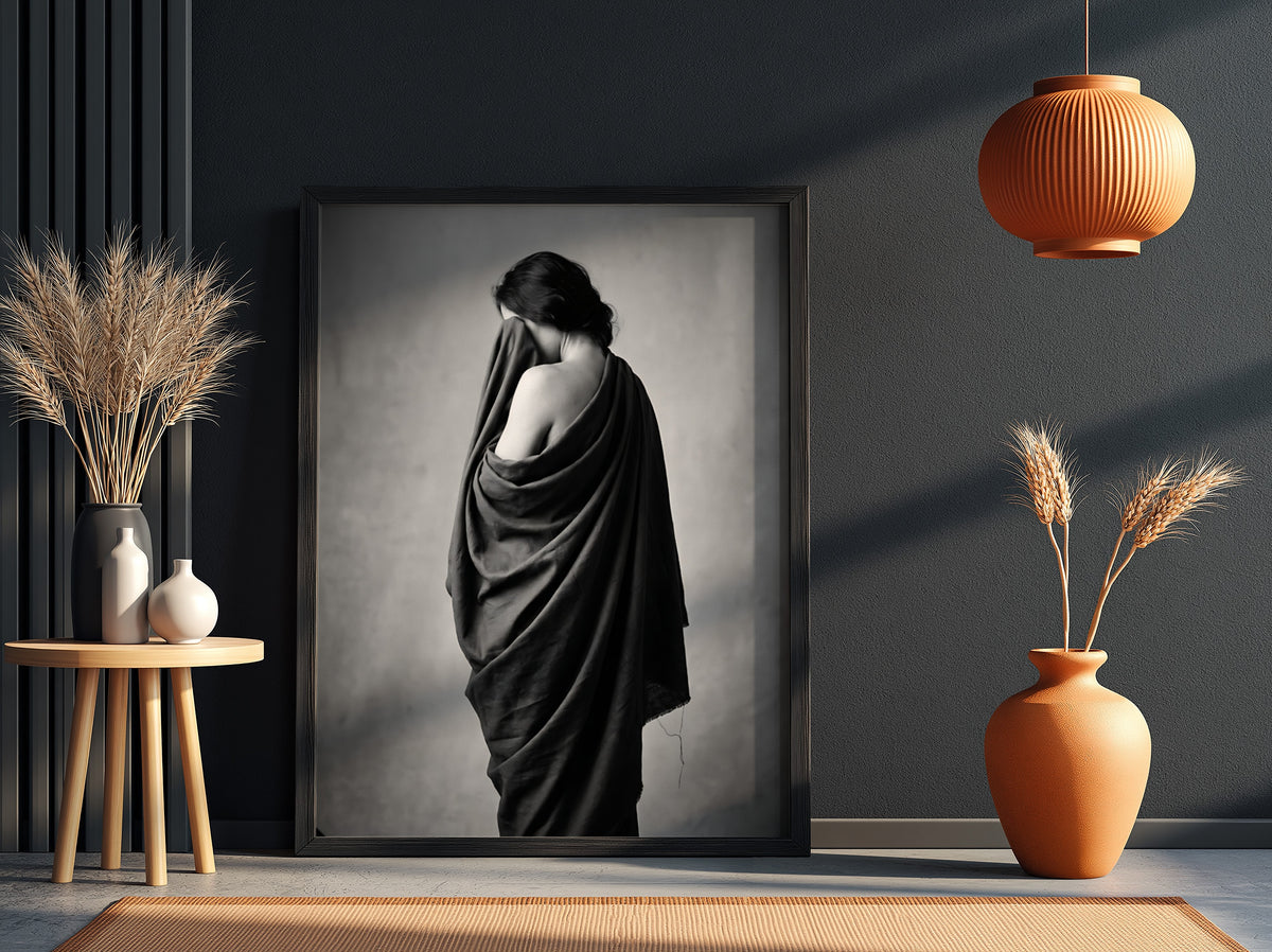 Black and white wall decor of a model draped in flowing dark fabric with soft shadows