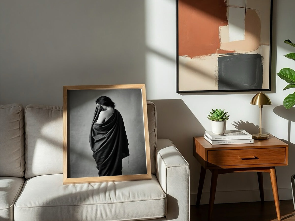Black and white wall decor of a model draped in flowing dark fabric with soft shadows