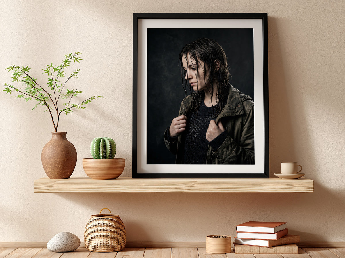 Framed poster showing model with rain-soaked hair in dark moody tones and contemplative pose
