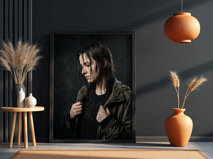Framed poster showing model with rain-soaked hair in dark moody tones and contemplative pose