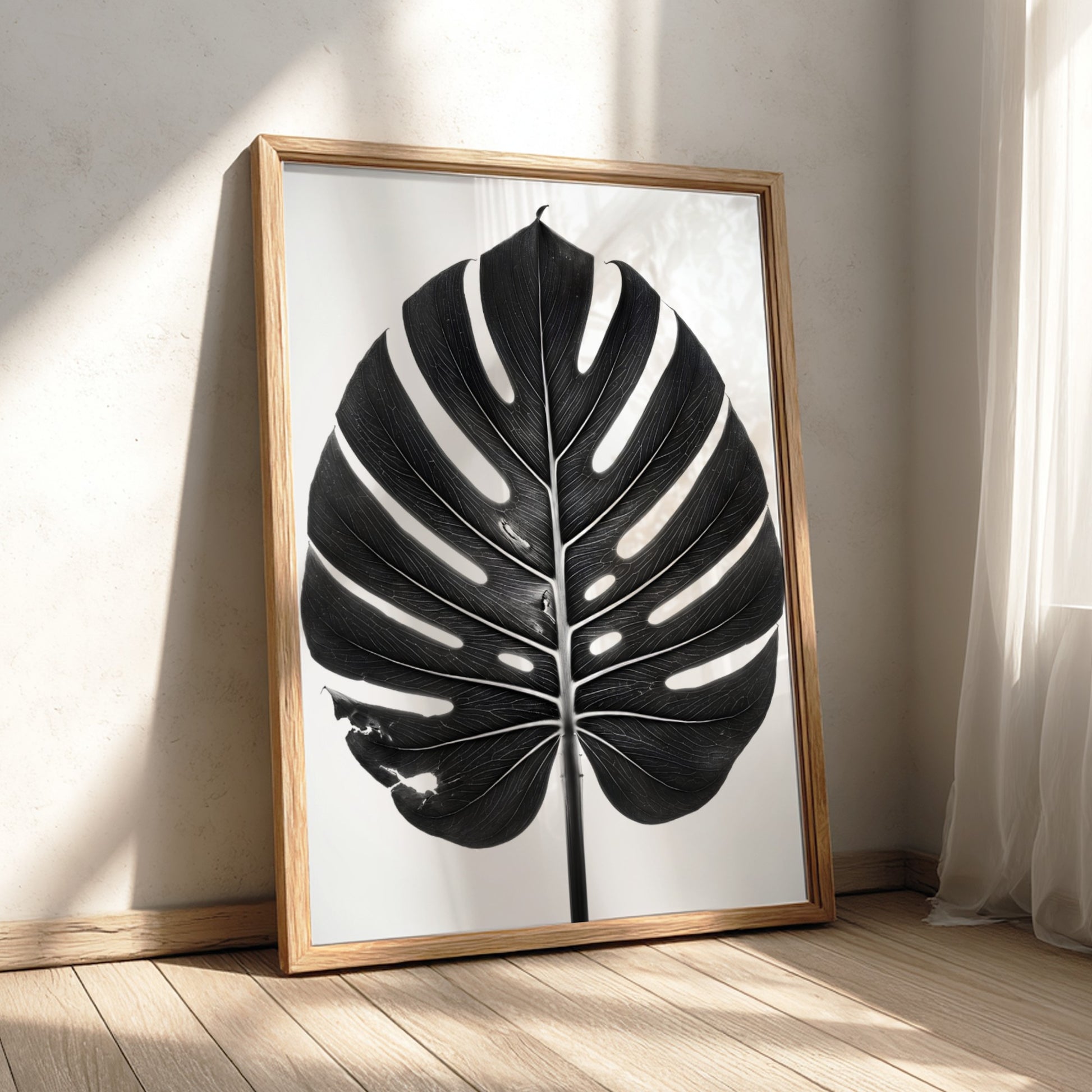Wall decor featuring a black Monstera leaf with backlit studio effect and natural wood frame on white