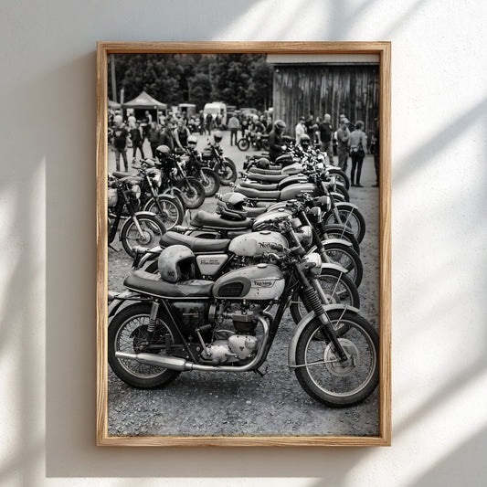 Black and white poster of vintage motorcycles parked in a row at an outdoor meet up with people in background