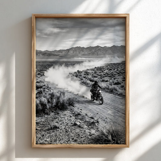 Black and white wall decor showing motorcyclist riding across dusty desert landscape with mountains