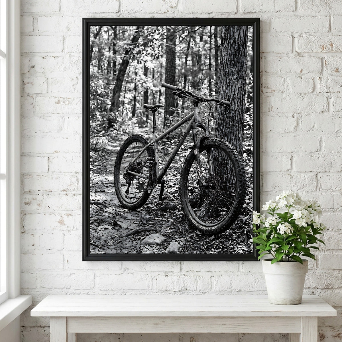 Black and white wall decor showing mountain bike resting against tree in forest with textured bark