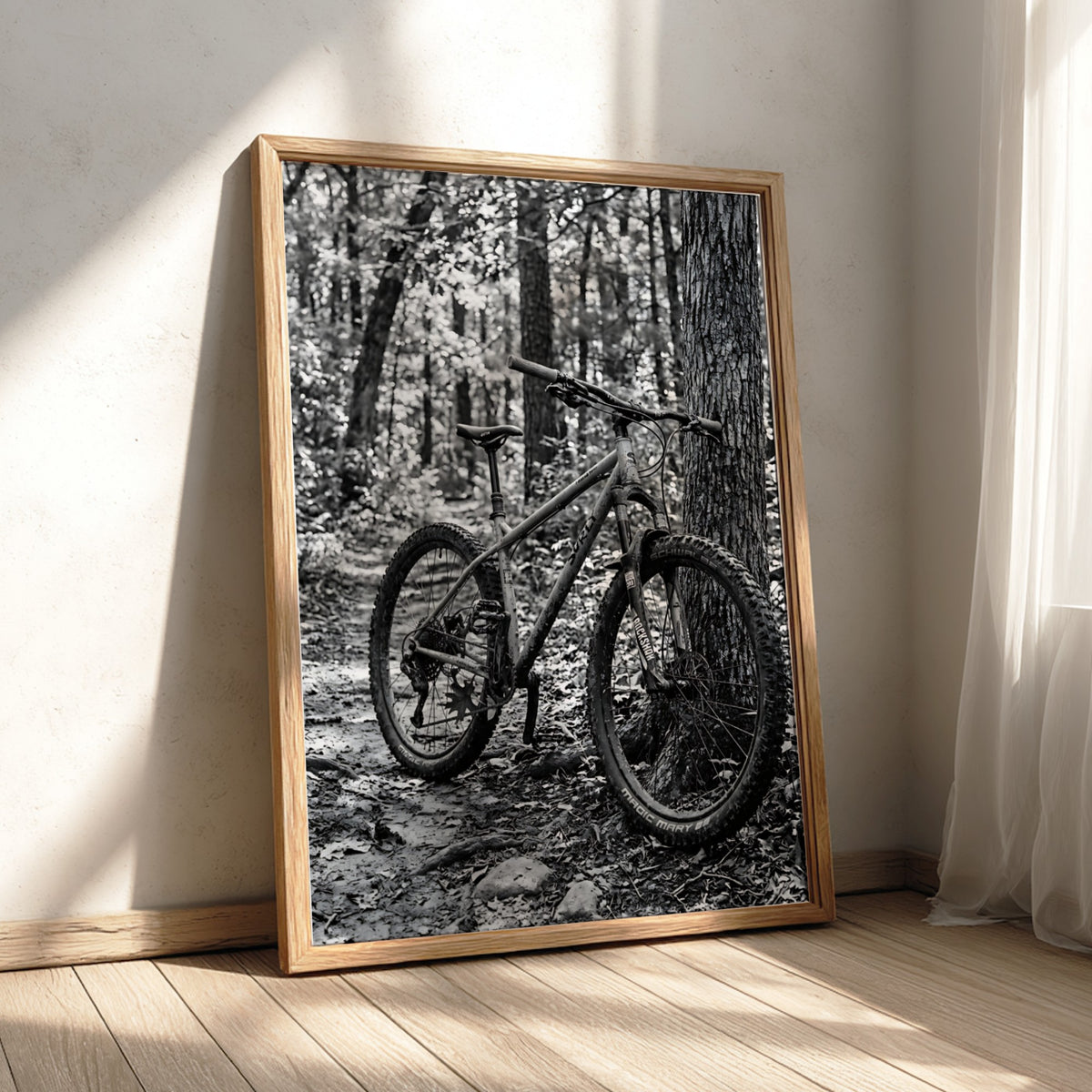 Black and white wall decor showing mountain bike resting against tree in forest with textured bark