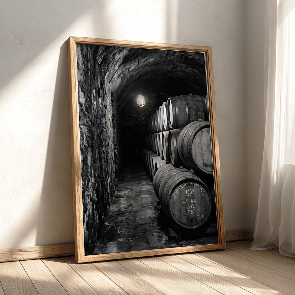 Wall decor featuring black and white photograph of oak wine barrels stacked in stone cellar under soft light