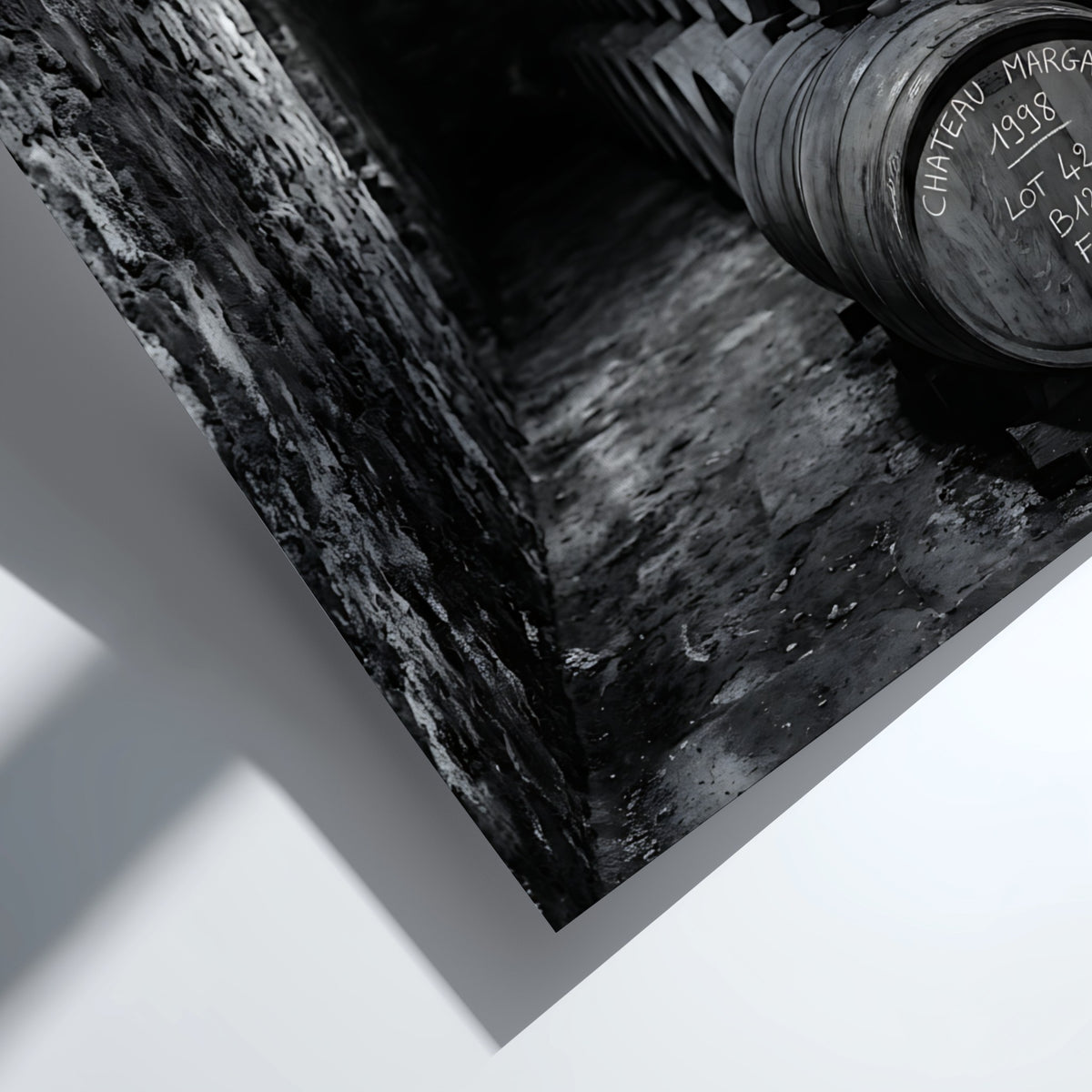 Wall decor featuring black and white photograph of oak wine barrels stacked in stone cellar under soft light