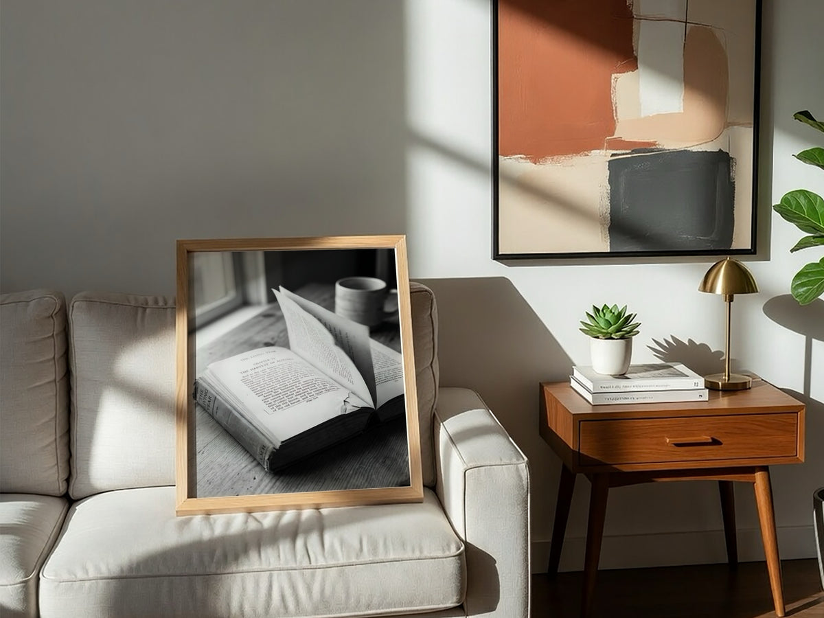 Black and white wall decor showing an open book with pages turning on a wooden surface with soft natural light