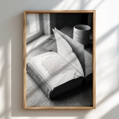 Black and white wall decor showing an open book with pages turning on a wooden surface with soft natural light