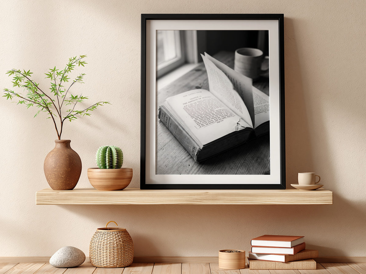 Black and white wall decor showing an open book with pages turning on a wooden surface with soft natural light