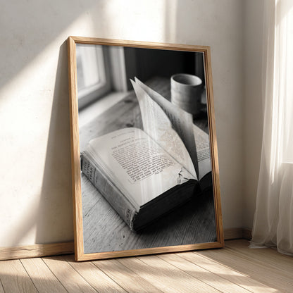 Black and white wall decor showing an open book with pages turning on a wooden surface with soft natural light