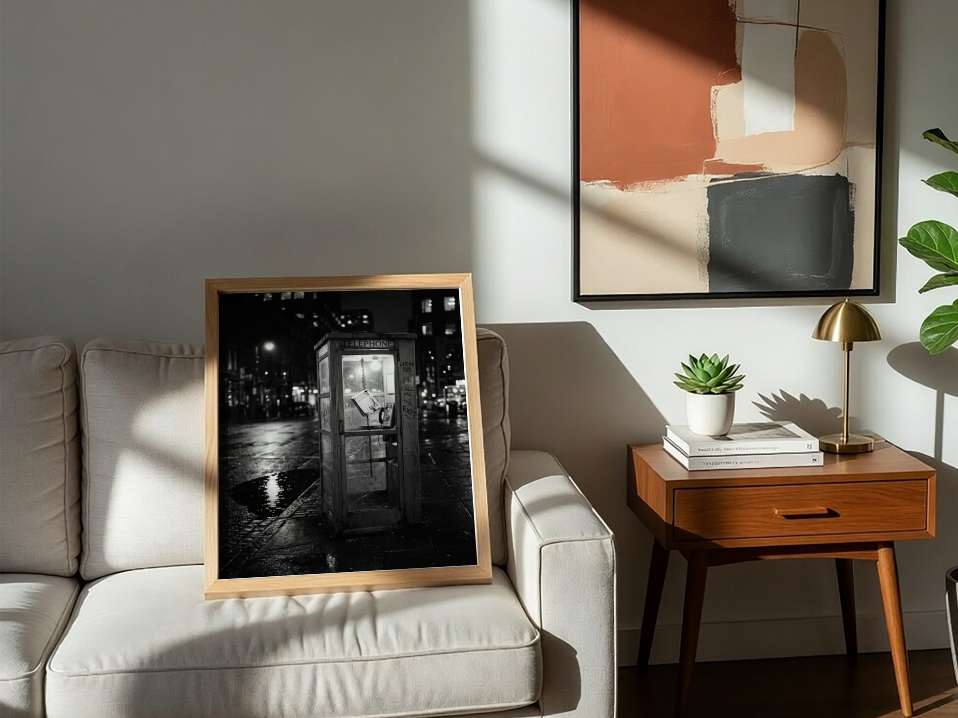 black and white wall decor of illuminated phone booth on rainy city street corner at night