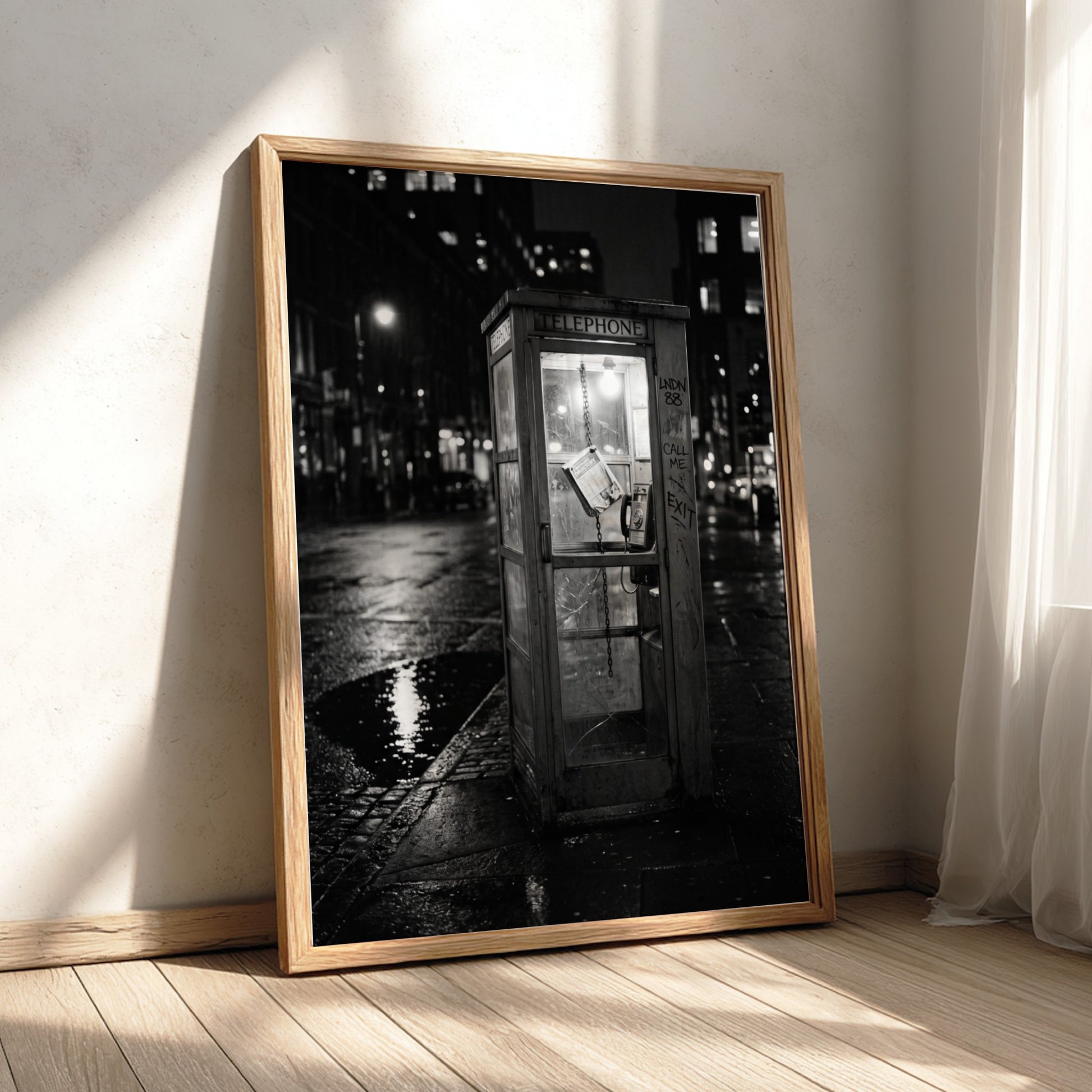 black and white wall decor of illuminated phone booth on rainy city street corner at night