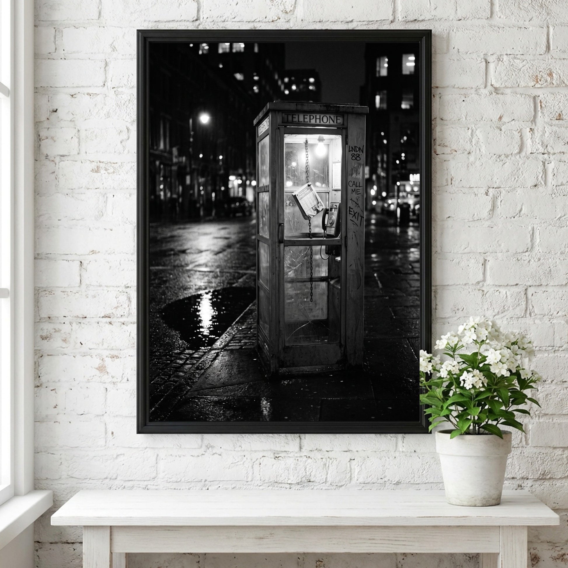 black and white wall decor of illuminated phone booth on rainy city street corner at night