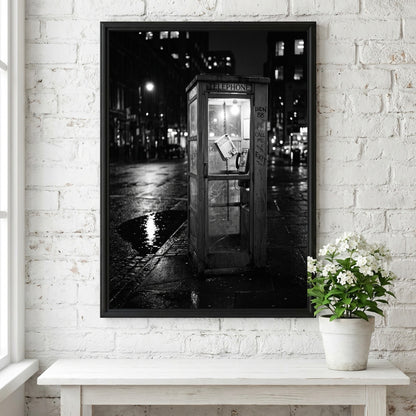 black and white wall decor of illuminated phone booth on rainy city street corner at night