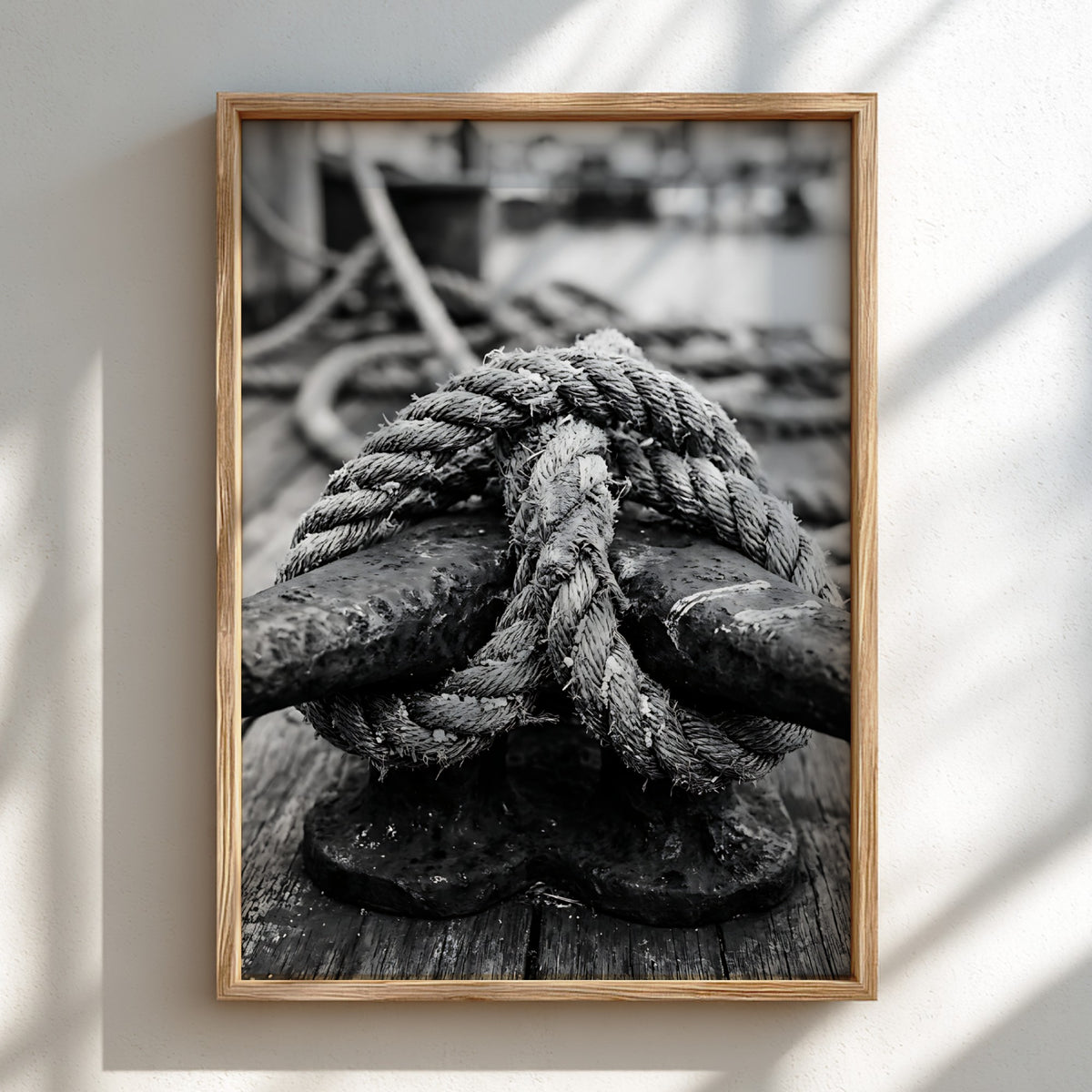 Nautical wall decor showing black and white close-up of rope tied around weathered deck cleat on wooden