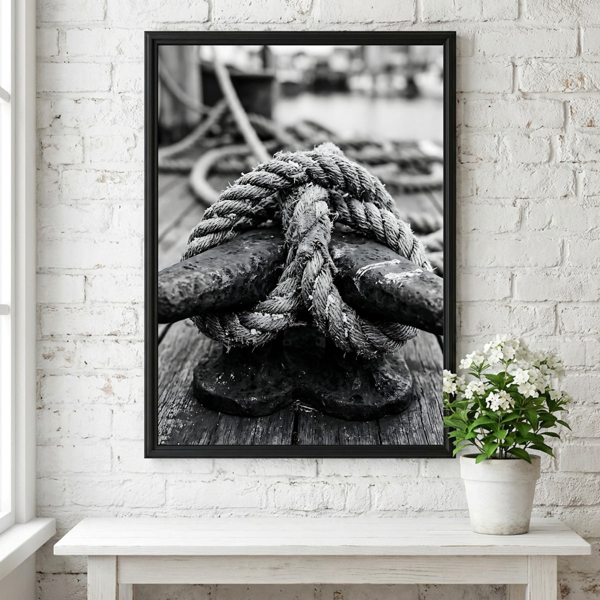 Nautical wall decor showing black and white close-up of rope tied around weathered deck cleat on wooden