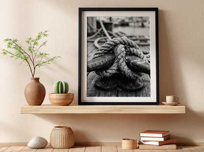 Nautical wall decor showing black and white close-up of rope tied around weathered deck cleat on wooden