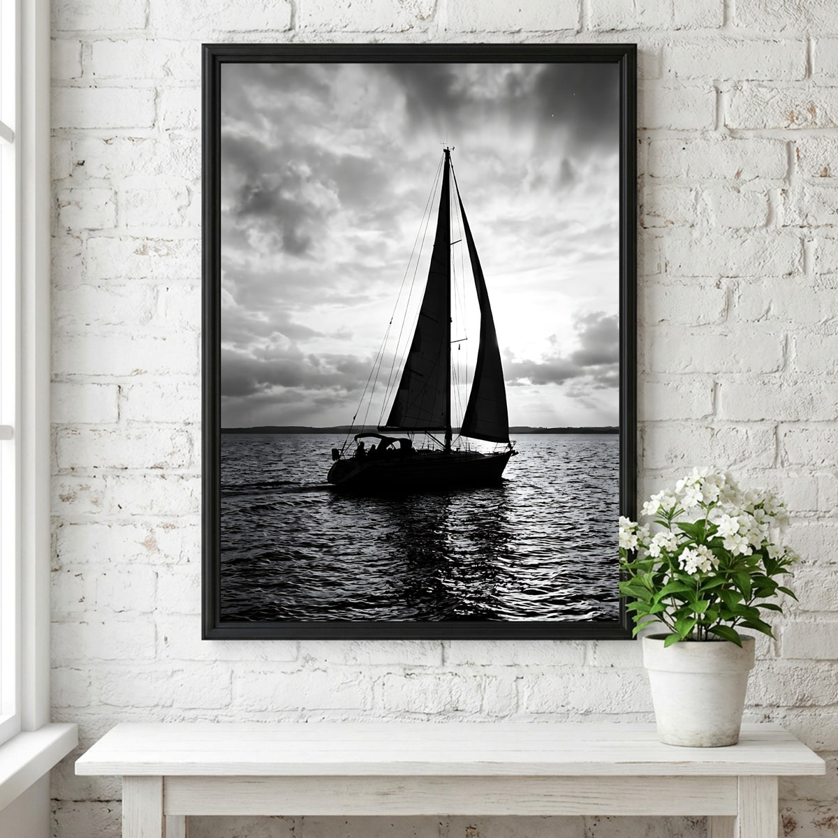 Black and white photographic wall decor featuring sailboat silhouette on water under bright cloudy sky