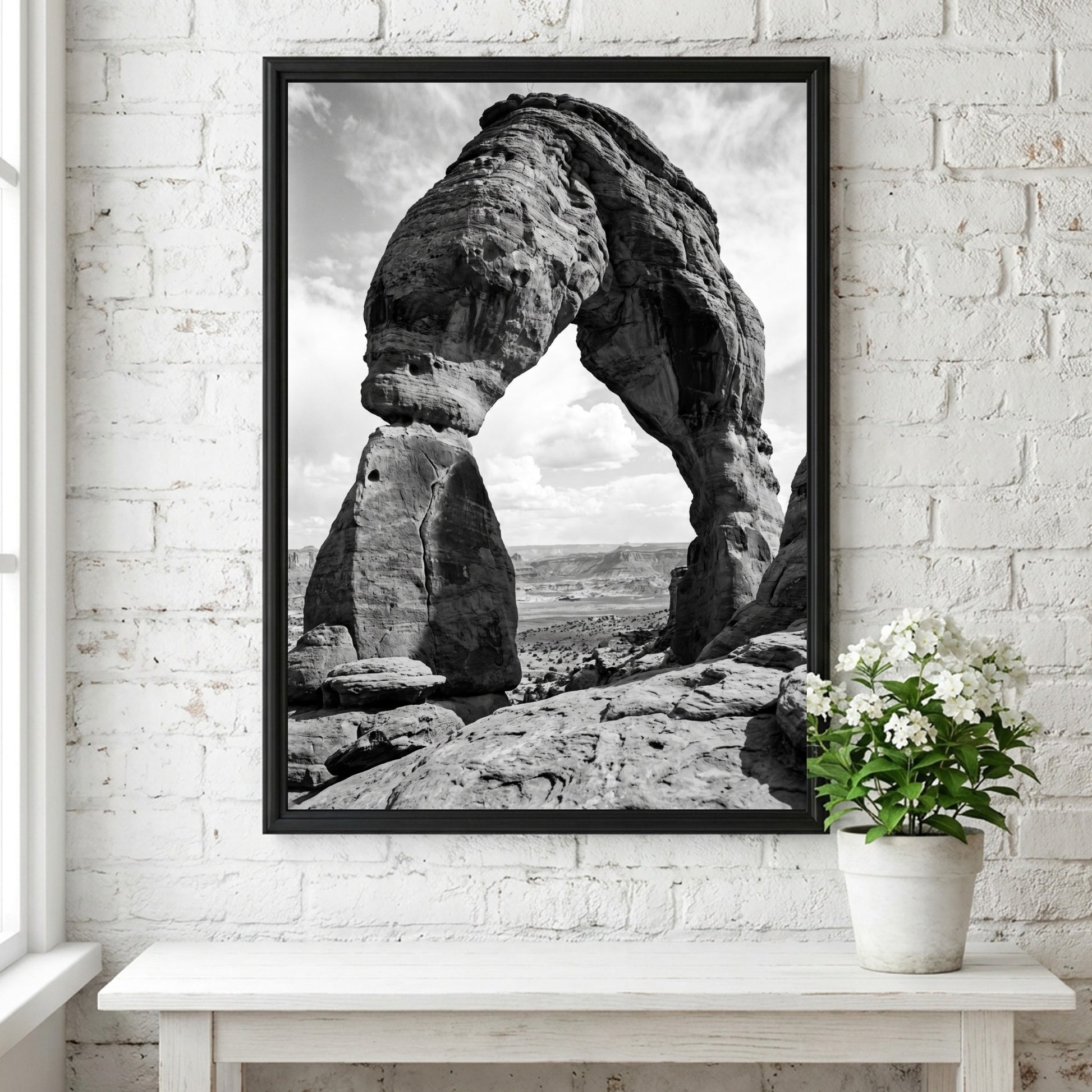 Black and white wall decor of sandstone arch in desert with textured rock and cloudy sky