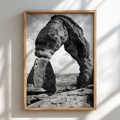 Black and white wall decor of sandstone arch in desert with textured rock and cloudy sky