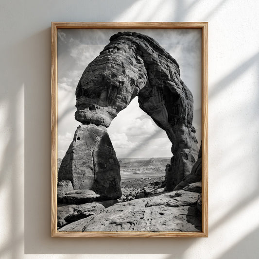 Black and white wall decor of sandstone arch in desert with textured rock and cloudy sky