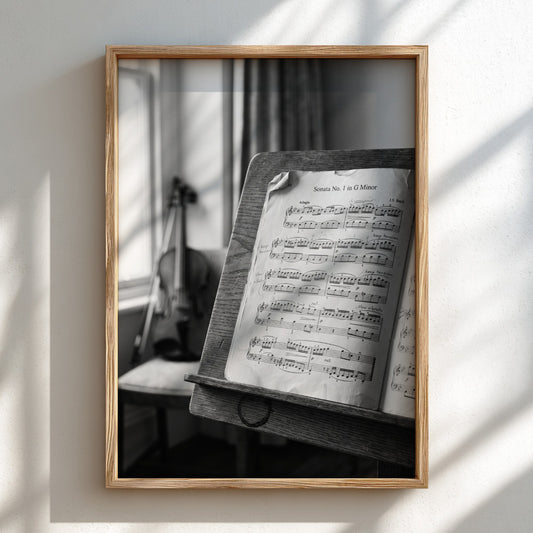 Black and white poster of sheet music on wooden stand with blurred violin in background