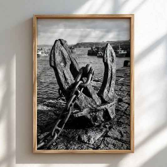 Black and white poster showing ship anchor on textured harbor wall with boats and water background