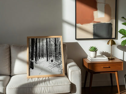 Framed wall decor showing a snowy forest winter landscape with tall bare trees and fresh white snow