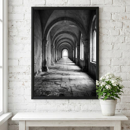 Black and white wall decor of stone corridor with rounded arches and textured stone floor