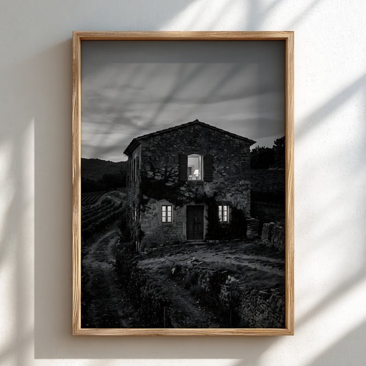 Black and white wall decor featuring a stone vineyard estate house at dusk with shutters and winding path