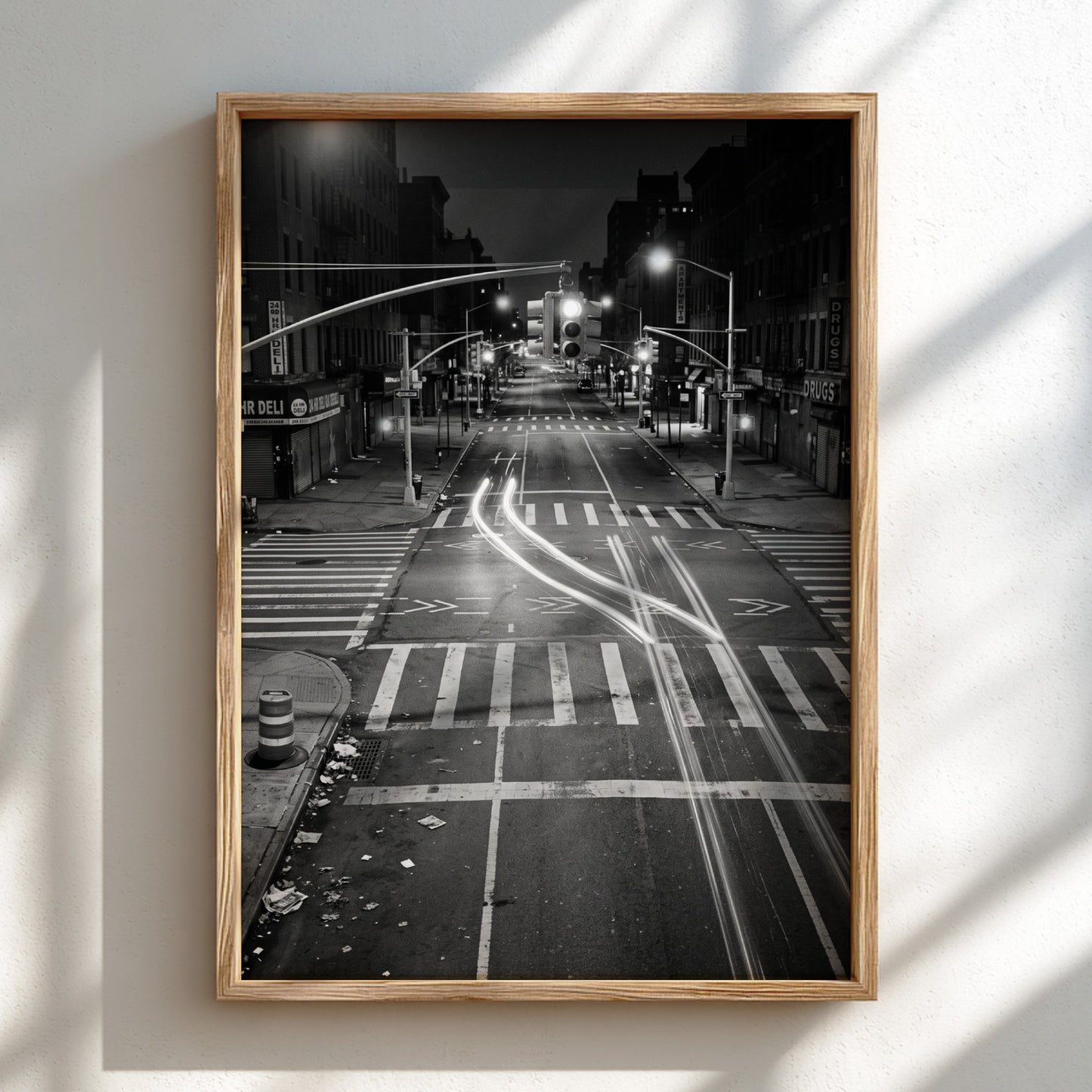 black and white wall decor of taxi passing empty city intersection with light trails at night