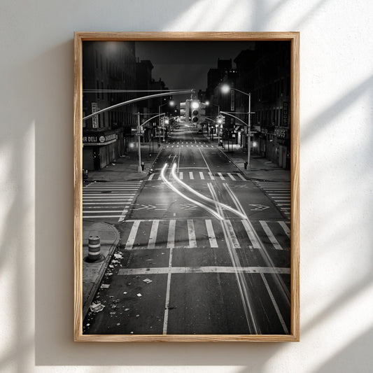black and white wall decor of taxi passing empty city intersection with light trails at night