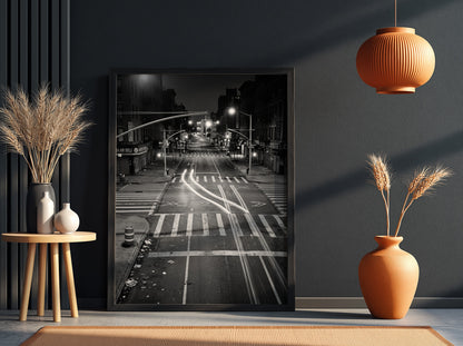 black and white wall decor of taxi passing empty city intersection with light trails at night