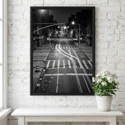 black and white wall decor of taxi passing empty city intersection with light trails at night
