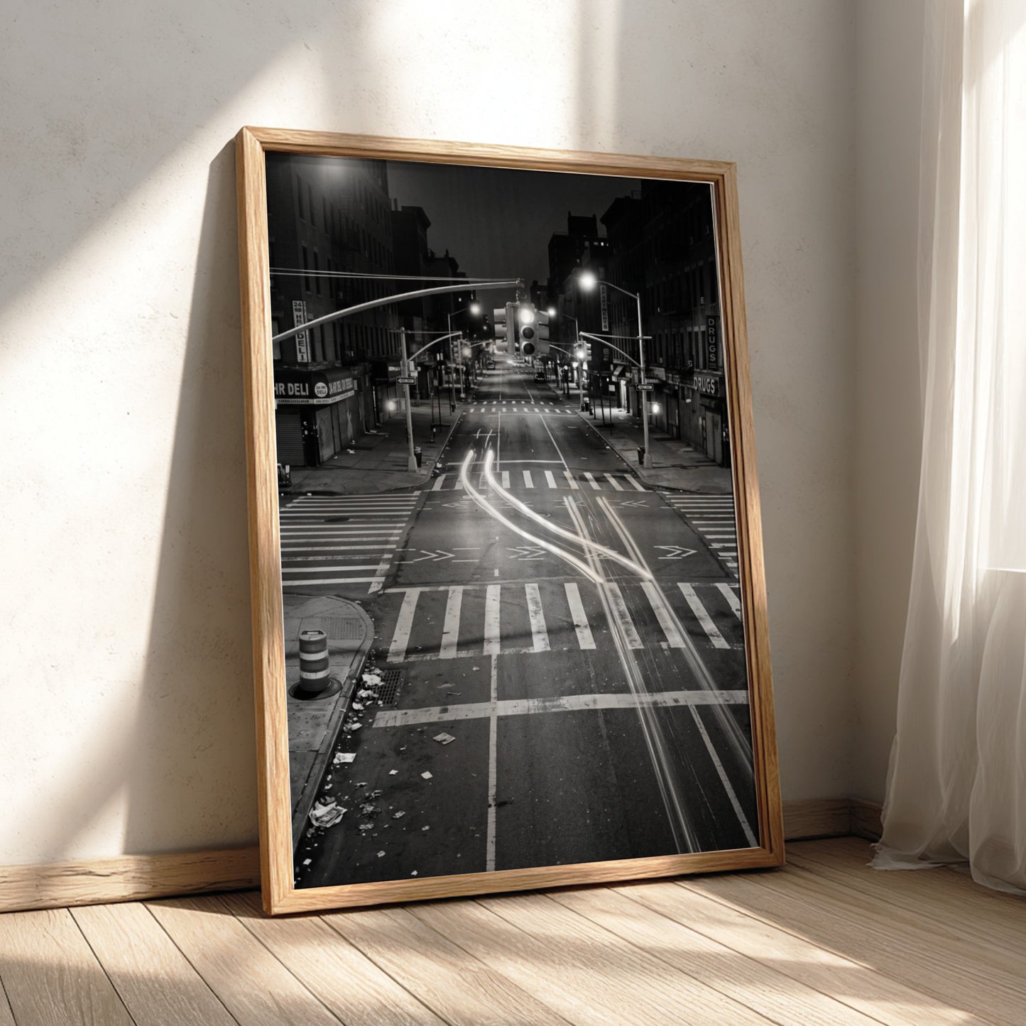 black and white wall decor of taxi passing empty city intersection with light trails at night
