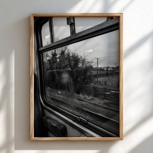 Black and white photographic wall decor of train window passing blurred landscape with trees and tracks