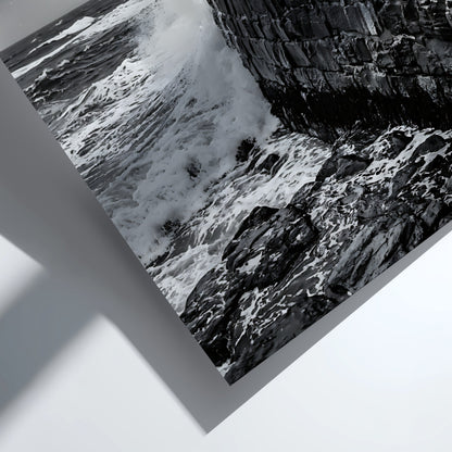 Black and white poster of waves crashing against rugged stone wall under cloudy sky with seagull flying