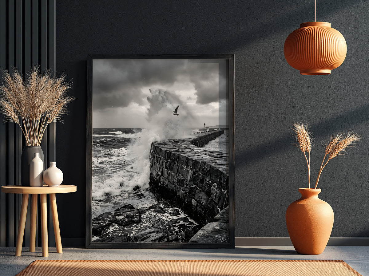 Black and white poster of waves crashing against rugged stone wall under cloudy sky with seagull flying
