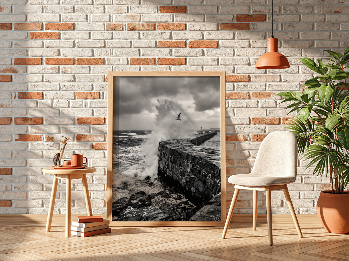 Black and white poster of waves crashing against rugged stone wall under cloudy sky with seagull flying