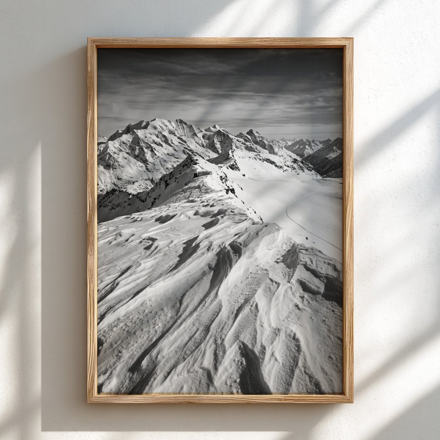 Photographic wall decor of black and white wind sculpted snow ridge with alpine mountains and textured snow