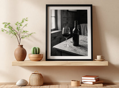 Wall decor poster showing black and white wine bottle and glass on rustic wooden table with soft window light