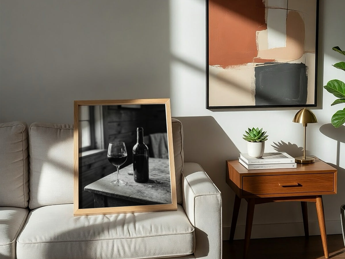 Wall decor poster showing black and white wine bottle and glass on rustic wooden table with soft window light