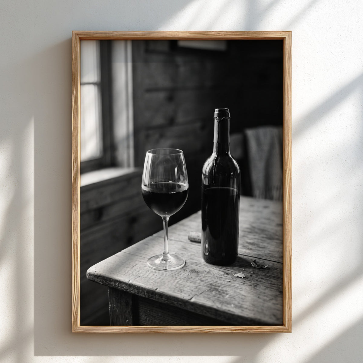 Wall decor poster showing black and white wine bottle and glass on rustic wooden table with soft window light