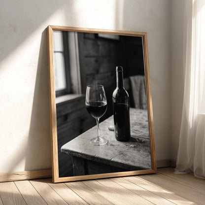 Wall decor poster showing black and white wine bottle and glass on rustic wooden table with soft window light