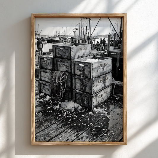 Black and white wall decor showing wooden crates stacked on a dockside with fishing boats in background